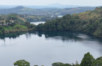 Calm crater lake surrounded by forested hills